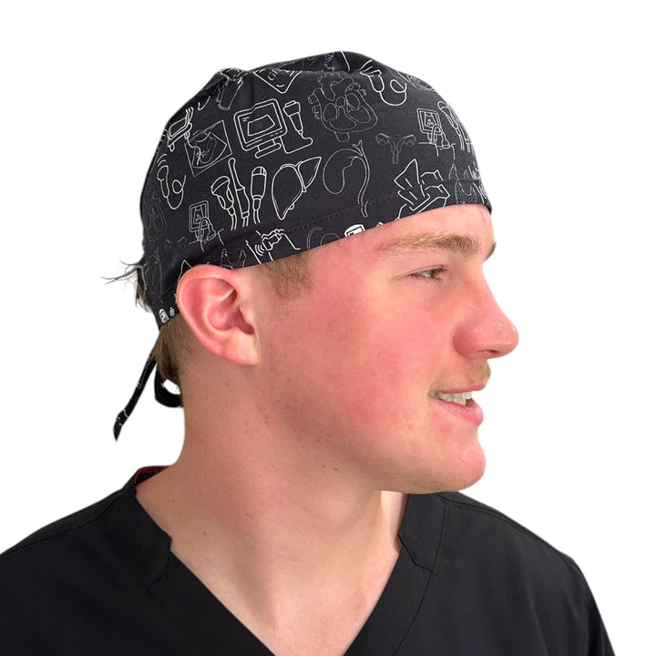 A man in profile wearing a black surgical scrub cap with white medical-themed line drawings, set against a plain white background.